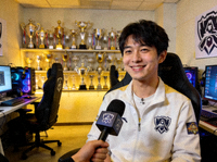 退役电竞选手微笑在训练基地接受专访，背景是满墙的奖杯